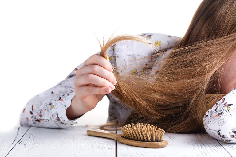 a young woman struggling with tangled hair and split ends