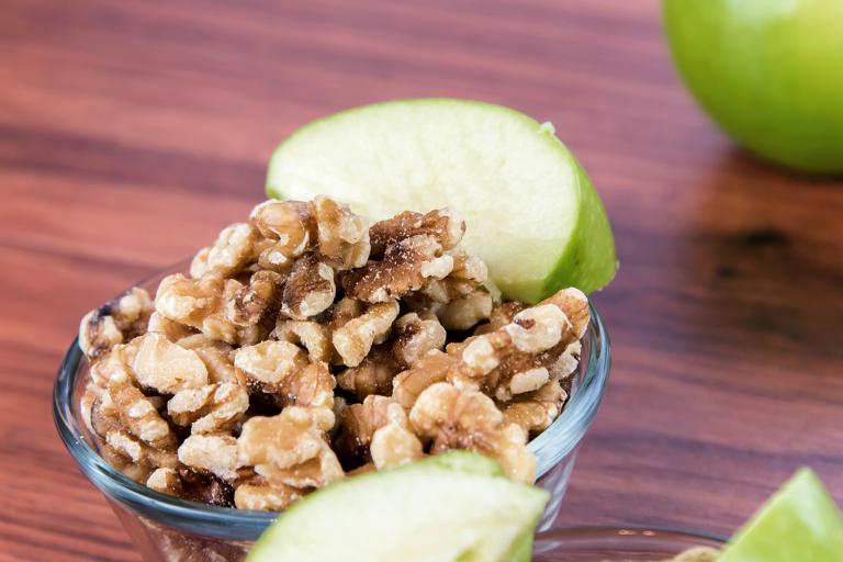 A bowl of chopped walnuts and green apple slices